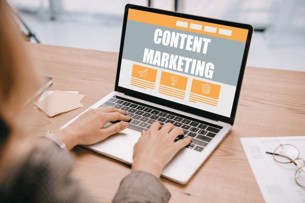 a woman typing on a laptop with the words content marketing on the screen