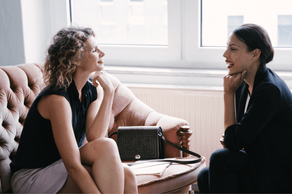 two women sitting on a couch talking to each other