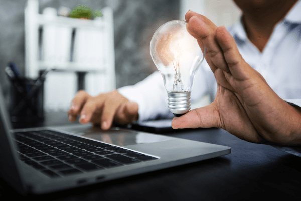 a man holding a light bulb over a laptop